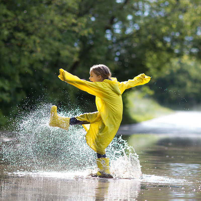 A young girl playing in the puddles